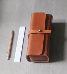 a brown leather case next to a pen and ruler