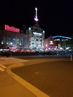 an empty parking lot in front of a large building with a neon sign on it