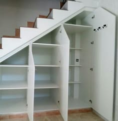 an open bookcase under the stairs in a house