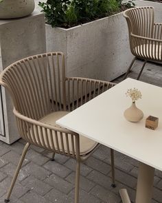 two chairs sitting next to each other near a table with a vase on top of it