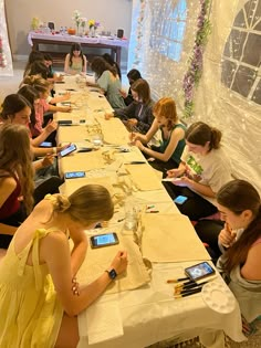 a group of people sitting at a long table with cell phones in their hands and writing on paper