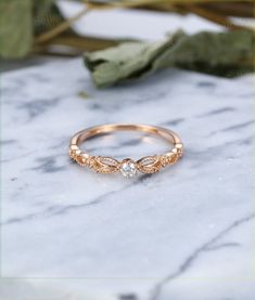 a rose gold ring with two small diamonds on the side, sitting on a marble surface