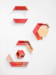 three red and orange shelves on a white wall with one shelf in the shape of an arrow