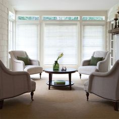 a living room with two chairs and a coffee table in front of a window filled with blinds