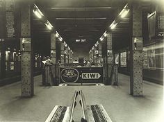 an empty train station with benches and signs on the wall, in black and white