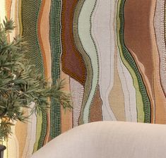 a potted plant sitting on top of a white chair next to a wall covered in multicolored stripes