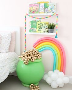 a green pot filled with gold coins next to a rainbow wall hanging above a bed