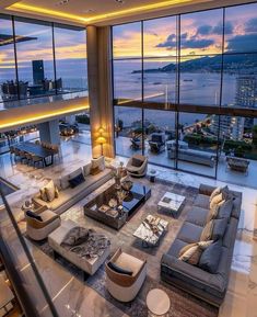 a living room filled with lots of furniture next to large windows overlooking the city at night