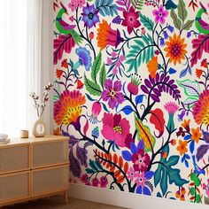 a colorful floral wallpaper in the corner of a room next to a dresser and window