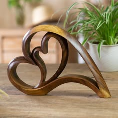 a wooden sculpture sitting on top of a table next to a potted plant