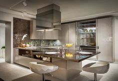 a modern kitchen with stainless steel appliances and marble counter tops, along with white stools