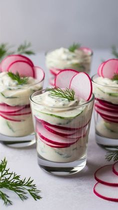 four small glasses filled with food and garnished with radishes on the side