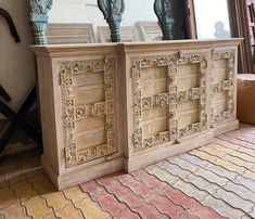 two wooden sideboards with carved designs on the top and bottom, sitting in front of a window