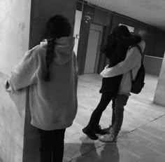 two girls standing next to each other in an empty building with their arms around each other