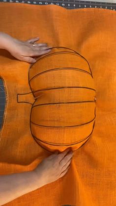 someone is making a pumpkin pillow out of an orange material with black stitching on it