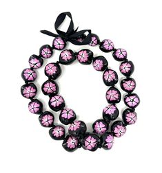 a pink and black beaded bracelet with flowers on the front, attached to a black ribbon