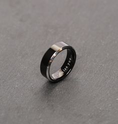 a black and silver wedding ring on a gray surface