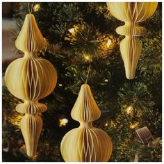 three yellow paper ornaments hanging from a christmas tree