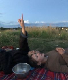 a man laying on top of a blanket next to a metal bowl