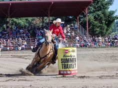 a man riding on the back of a brown horse in front of a crowd at a rodeo