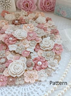 there are many flowers on the doily next to pearls and other things in the background