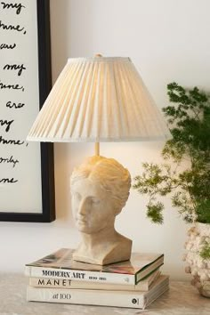 a lamp sitting on top of two books next to a vase with flowers in it