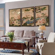 a living room with three paintings on the wall and two couches in front of it