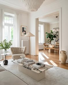 a living room filled with furniture and a large white rug on top of a hard wood floor