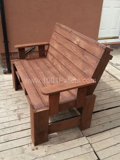 a wooden bench sitting on top of a wooden floor next to a building with a door