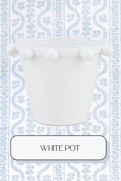 a white pot sitting on top of a blue and white wall