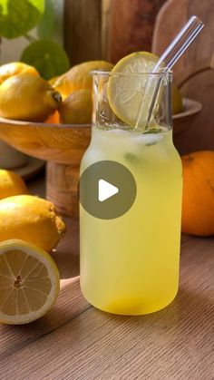 a lemonade in a glass with a straw next to some lemons and oranges