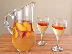 pitcher and two glasses filled with liquid on a wooden table next to each other,