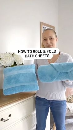 a woman holding two blue bath sheets in front of a mirror with the words how to roll & fold bath sheets