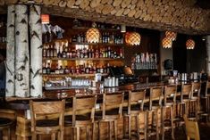 a bar with wooden chairs and lots of bottles