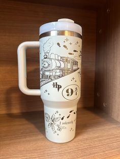 a travel mug with an image of a train on it sitting on a wooden shelf