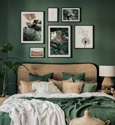 a bedroom with green walls and pictures on the wall above the bed, along with a wicker headboard