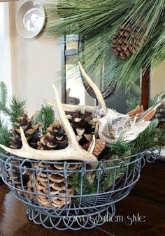 a basket filled with pine cones and deer antlers on top of a wooden table