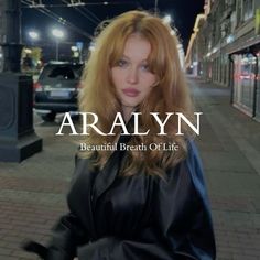 a woman with red hair is standing on the sidewalk in front of a city street