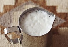 a metal pitcher filled with white liquid on top of a rug