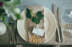 a place setting with silverware, napkins and greenery on the table for an elegant wedding reception