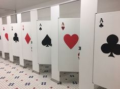 several playing cards are lined up on the wall next to each other in this public restroom