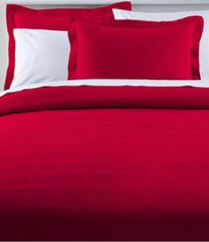 a red bed with white pillows and two pillow cases on top of the headboard