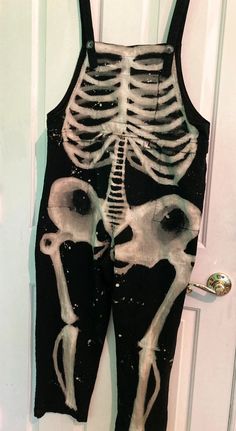 an image of a skeleton painted on the back of a pair of overalls that is hanging from a door