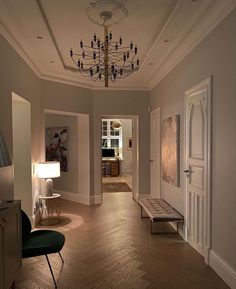 an empty room with a chandelier and two green chairs in front of the door