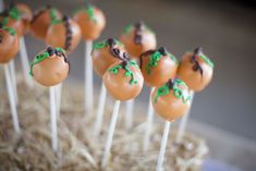 cake pops with chocolate frosting and green sprinkles on sticks in hay