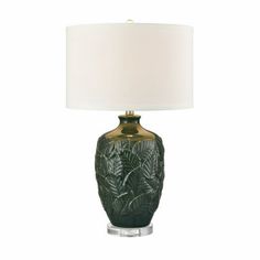 a green lamp with a white shade on the base and a leaf design on the bottom