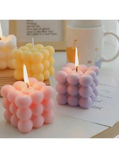 three candles sitting on top of a table next to a coffee cup and notepad