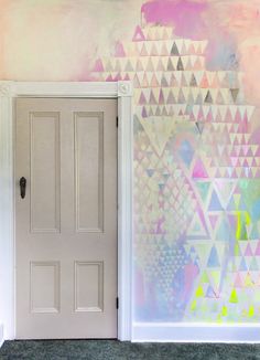 an open door in front of a colorful wall with triangles painted on the walls and below it