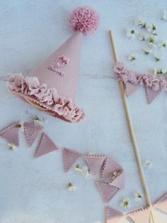 a pink party hat sitting on top of a table next to a stick and flowers