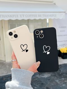 two people holding up their phone cases with hearts and crossbones drawn on them